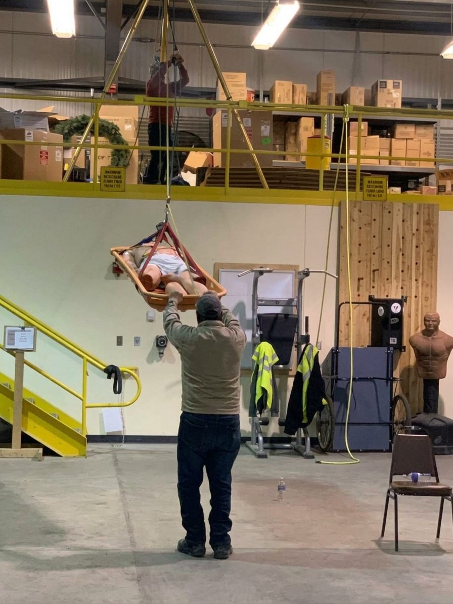 Trainee lowering a rescue litter with a manikin patient during emergency responder training